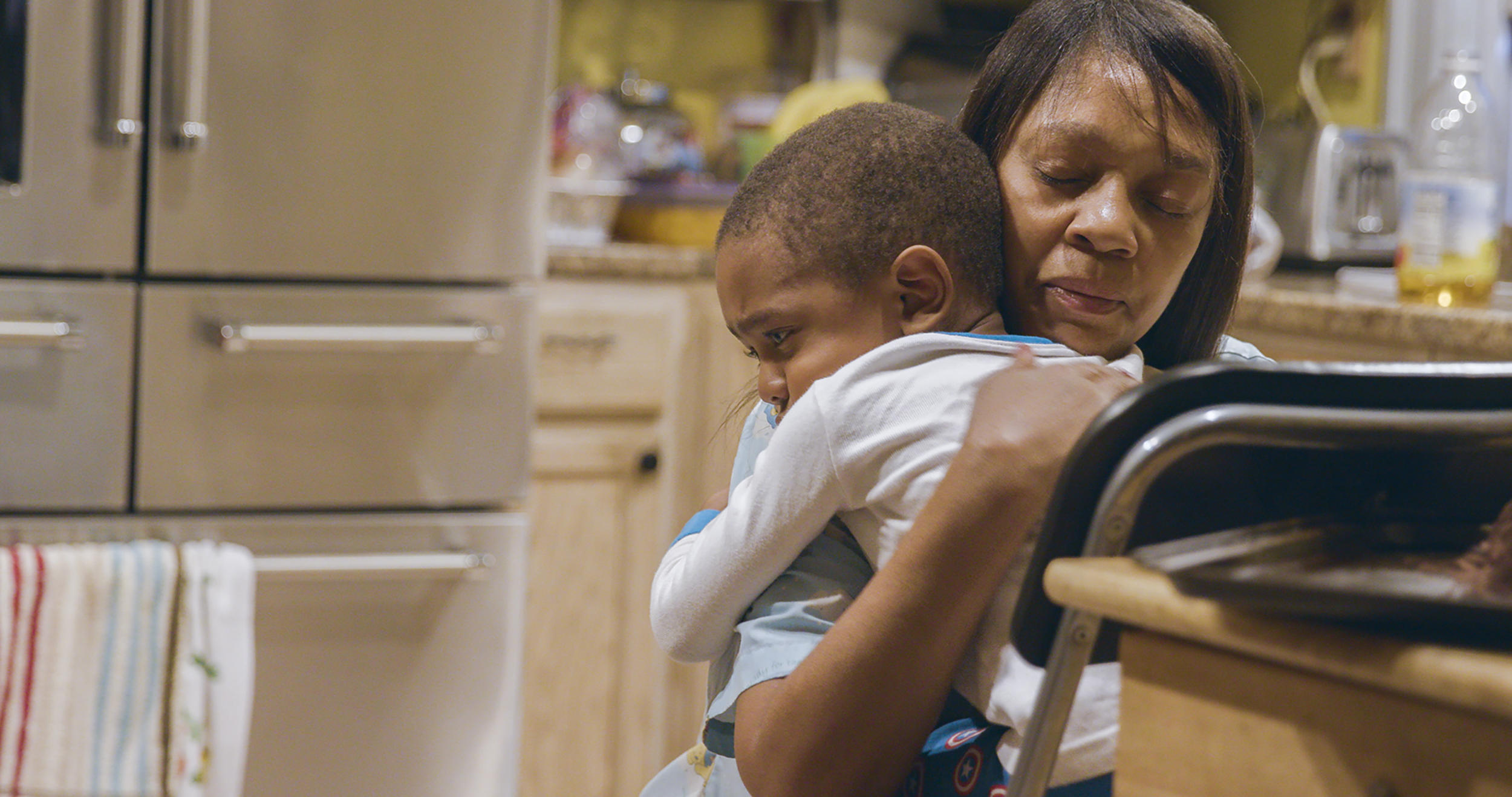 Woman and young boy embracing in kitchen